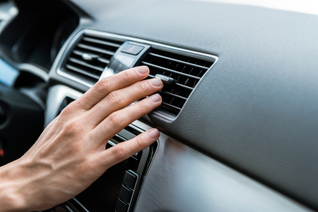 man touching air conditioner switch in car