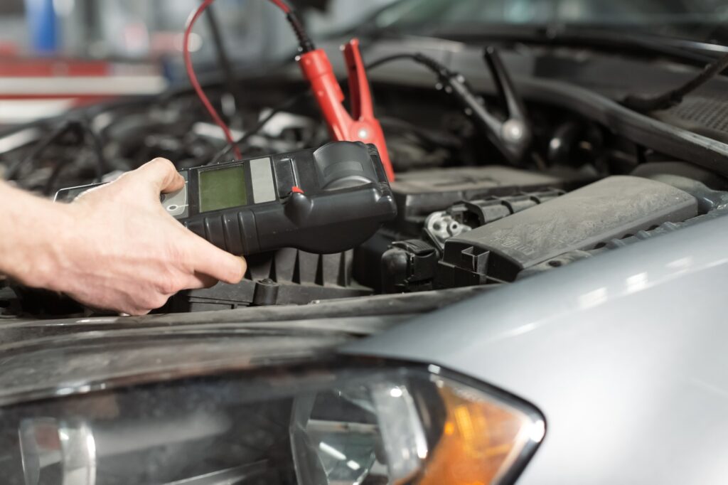 Technician hands measure the voltage of the battery in the car at service station