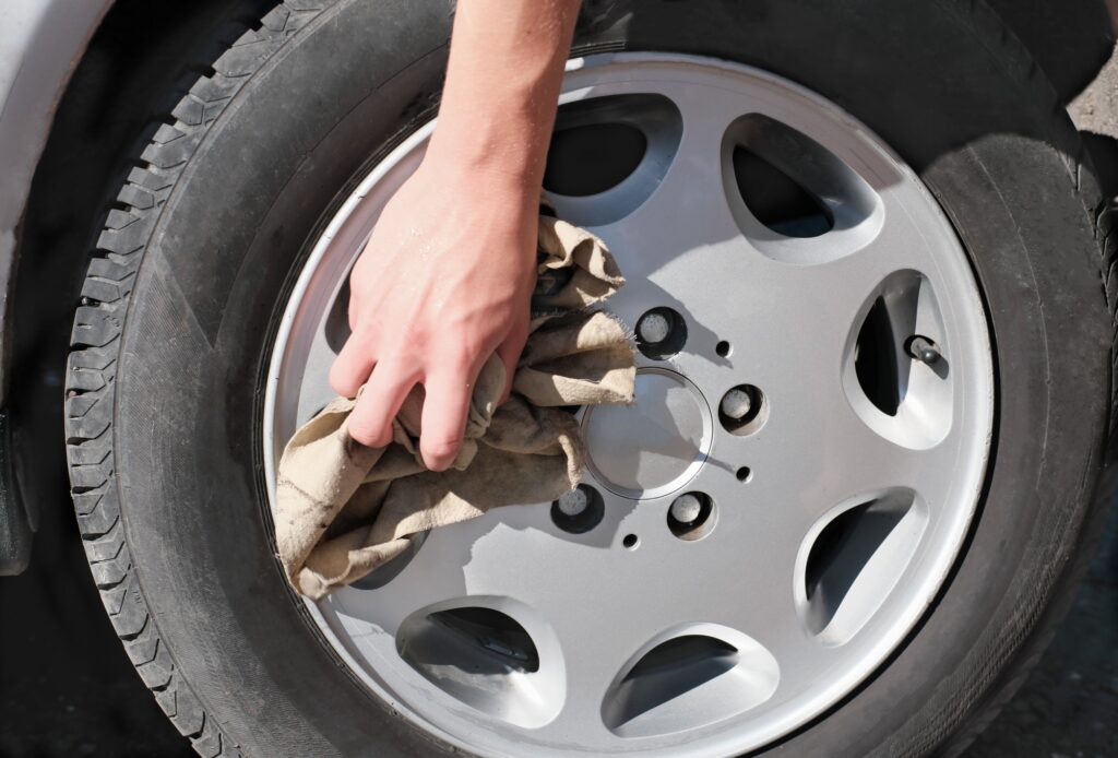 hand cleaning car wheel rim with a rag. car washing and cleaning concept