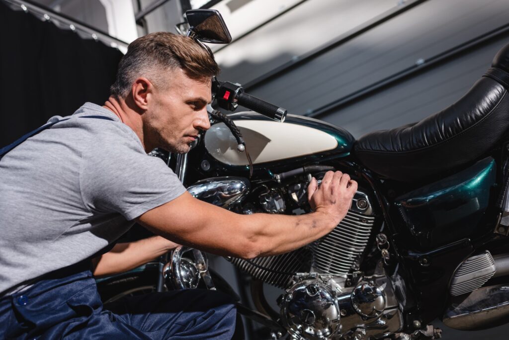 mechanic checking motorbike engine in garage