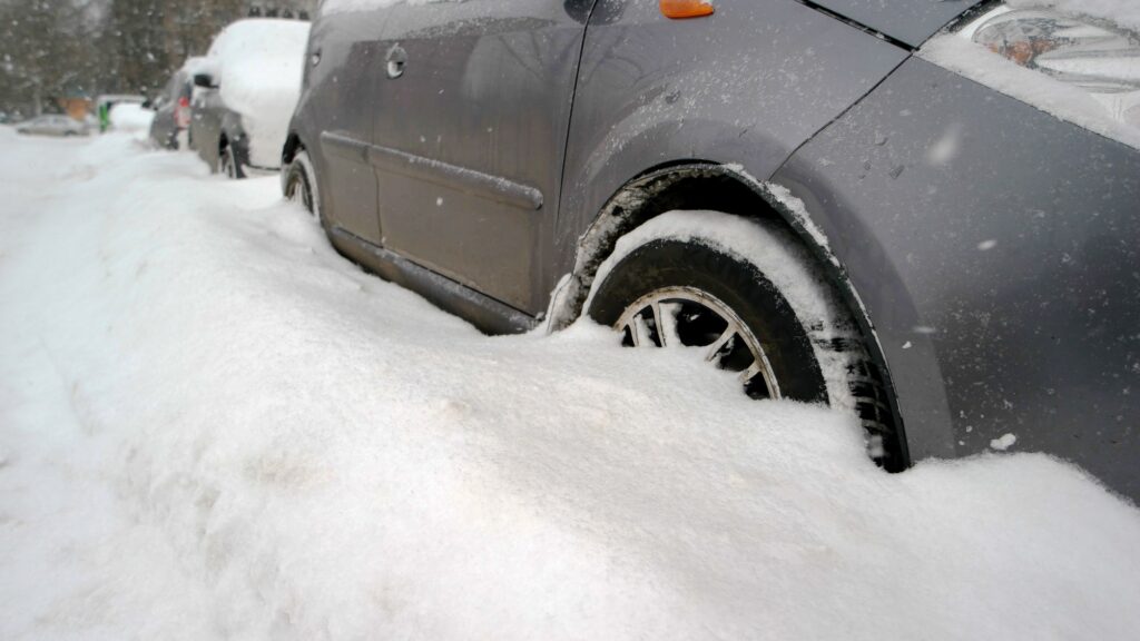 Wheel of car is stuck in snow.