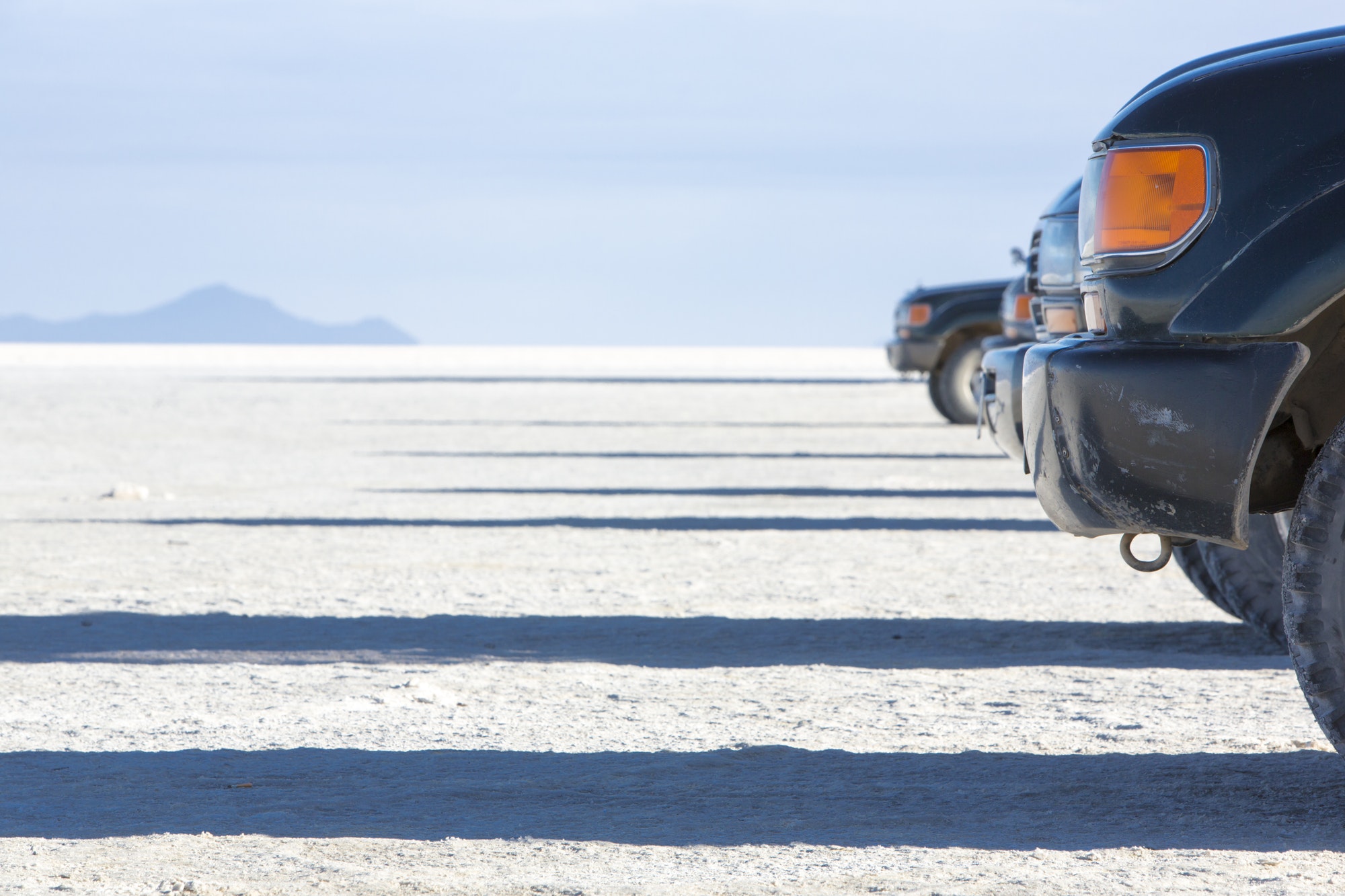 Group of 4x4 sides on the Salar of Uyuni with blue sky
