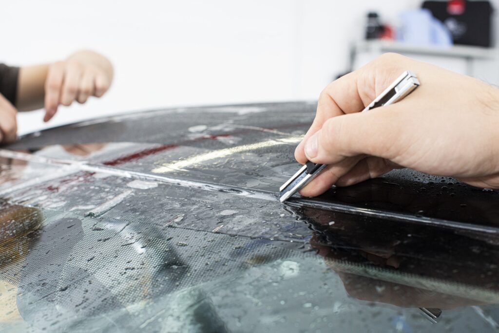 Applying a protective film with tools for work. Car detailing