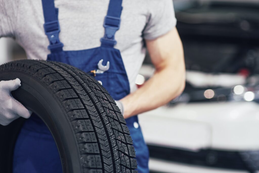 Mechanic holding a tire tire at the repair garage. replacement of winter and summer tires