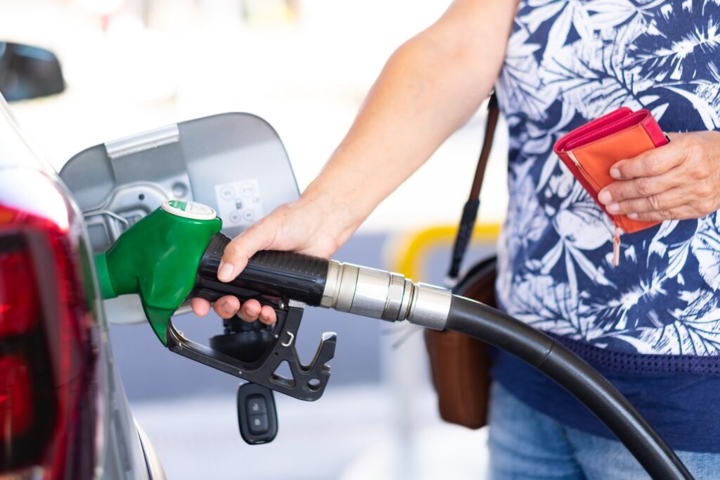Woman holding petrol gasoline fuel pump to refuel her silver car at the service station