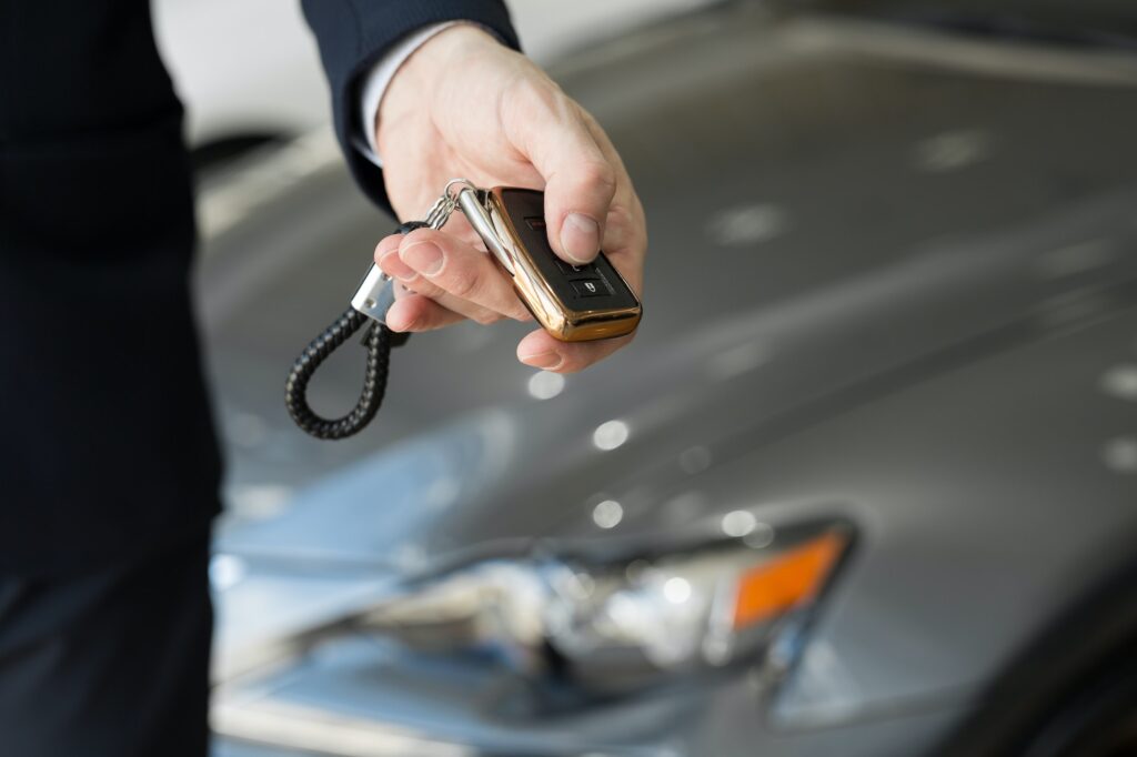 A car dealer with a key in a car dealership close-up
