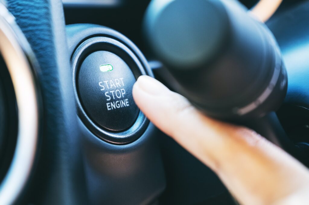 Closeup image of a finger pressing on a start stop engine button in a car